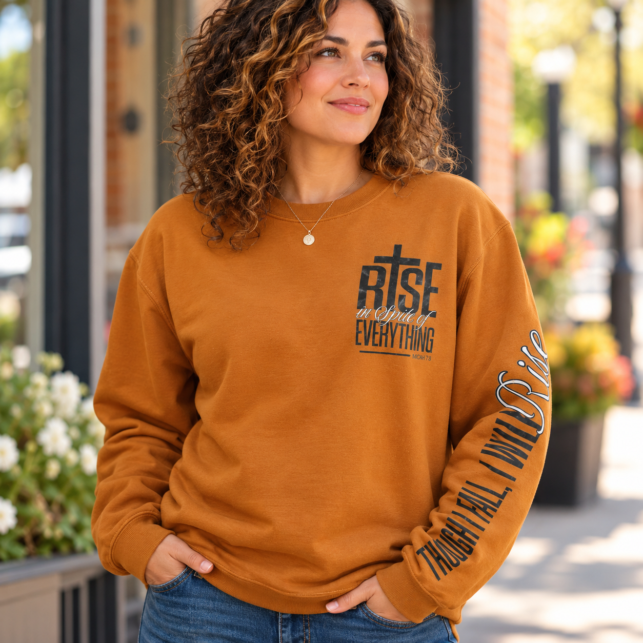 Front of burnt orange RISE Micah 7:8 crewneck sweatshirt with printed sleeve